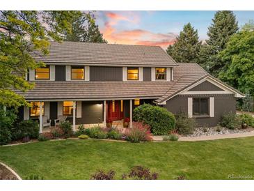 Charming two-story home featuring a landscaped yard and a welcoming front porch with beautiful sunset at 6128 S Coventry E Ln, Littleton, CO 80123