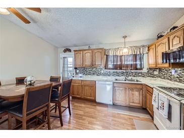 Cozy eat-in kitchen boasts stainless steel appliances, wood cabinets, and a stylish backsplash at 12425 Bellaire Dr, Thornton, CO 80241