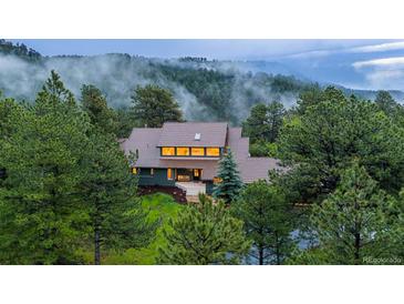 Secluded two-story home enveloped by lush trees and rolling hills with misty mountain views at 1952 Columbine Ct, Golden, CO 80401