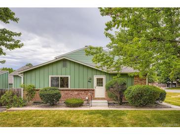 Charming exterior view of home with brick and green siding plus manicured lawn and landscaping at 400 S Balsam St, Lakewood, CO 80226