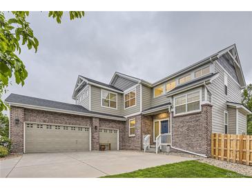 Charming two-story home with brick accents, three-car garage, manicured lawn, and inviting front porch at 6401 S Millbrook Way, Aurora, CO 80016