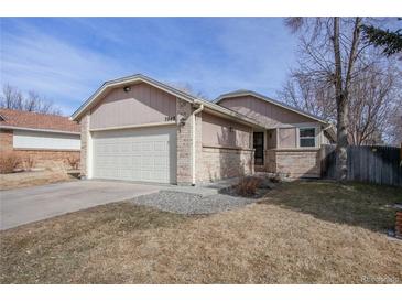 Charming single-story home with a two-car garage, lush lawn, and inviting brick accents at 7040 Routt St, Arvada, CO 80004