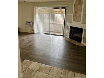 Bright living room featuring wood floors, fireplace and balcony access through sliding glass doors at 2231 Sable Blvd # 909, Aurora, CO 80011