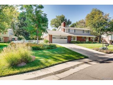 Charming two-story home featuring a well-manicured lawn and a long driveway leading to a two-car garage at 11754 W 28Th Ave, Lakewood, CO 80215