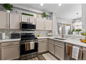 Bright kitchen features stainless steel appliances, granite countertops, tile backsplash, and light-colored cabinets at 9758 Laredo St # 18D, Commerce City, CO 80022