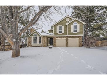 Two-story house with brick and siding, two-car garage, and snowy yard at 223 Durham Ct, Castle Pines, CO 80108