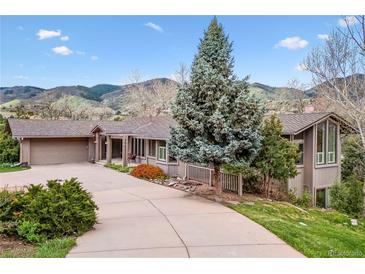 Spacious home exterior with a long driveway and mature landscaping, showcasing its curb appeal and serene setting at 6093 Willowbrook Dr, Morrison, CO 80465