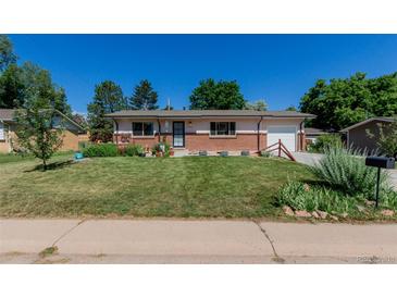 Charming single-story home with a well-manicured lawn, beautiful flowerbeds, and a brick facade at 6043 S Cody Way, Littleton, CO 80123
