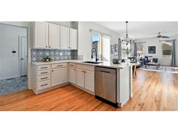Bright open kitchen featuring white cabinetry, quartz countertops, stainless appliances, and eat-in bar at 8645 Coors St, Arvada, CO 80005