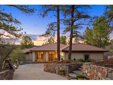 Charming single-story home with a tile roof, mature trees, and lush landscaping at 858 Swandyke Dr, Castle Rock, CO 80108