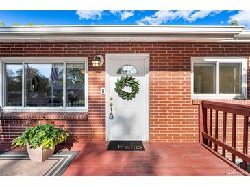 Charming brick home featuring a bright white front door adorned with a wreath and a welcoming 'hello' mat at 6506 Lee St, Arvada, CO 80004