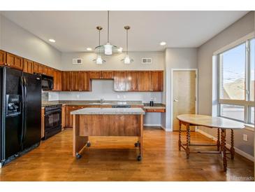 Bright kitchen featuring wood cabinets, granite counters, stainless steel appliances and a center island at 1057 W Century Dr # 112, Louisville, CO 80027