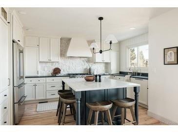 Bright kitchen with white cabinets, stone backsplash, an island with seating, and stainless steel appliances at 353 Columbine Ave, Broomfield, CO 80020