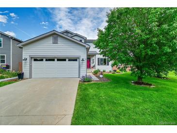 Charming two-story home featuring a well-manicured lawn, a two-car garage and a vibrant red front door at 215 Mcafee Cir, Erie, CO 80516