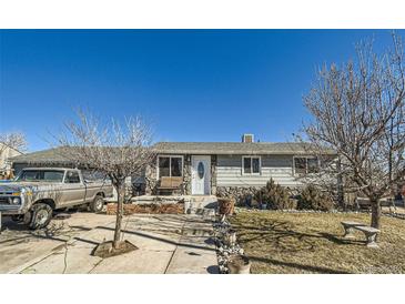 Charming single story home with stone accents, well-manicured lawn, and inviting front entrance at 7310 Carnation Pl, Commerce City, CO 80022