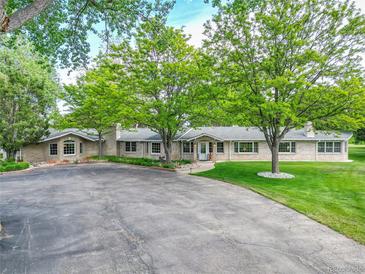 Expansive front yard with mature trees and a long driveway leading to a beautiful brick home at 7800 Indiana St, Arvada, CO 80007