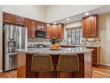 This beautiful kitchen features dark wood cabinets, granite countertops, and stainless steel appliances at 16278 E 105Th Way, Commerce City, CO 80022