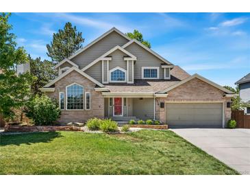 Charming two-story home boasts brick accents, mature landscaping, and a red front door at 1774 Brookside Dr, Highlands Ranch, CO 80126