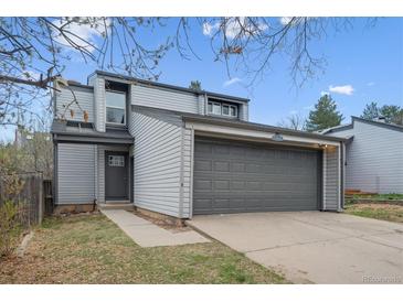 Two-story home with gray siding, a two-car garage, a front door and walkway surrounded by a lawn and trees at 17634 E Ohio Cir, Aurora, CO 80017