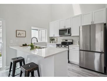 Bright kitchen features white cabinets, stainless steel appliances, and breakfast bar at 17634 E Ohio Cir, Aurora, CO 80017