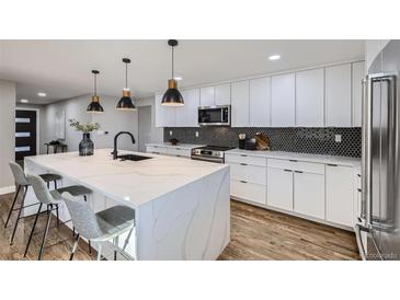 Renovated kitchen boasting white cabinets, hexagon backsplash, and a large island at 7076 S Newland St, Littleton, CO 80128