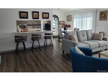 Inviting living room featuring hardwood floors, modern furniture, and an open concept layout to the kitchen at 9133 W Cedar Dr # A, Lakewood, CO 80226