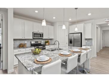 Bright kitchen with granite countertops, stainless steel appliances, and barstool seating at 24447 E Ada Ave, Aurora, CO 80018