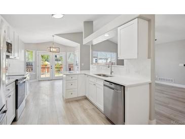 Bright kitchen featuring white cabinetry, stainless steel appliances, and hardwood floors at 765 Freestone St, Brighton, CO 80603