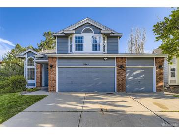 Charming two-story home featuring a three-car garage, blue siding, brick accents, and manicured lawn at 5645 S Himalaya Way, Centennial, CO 80015