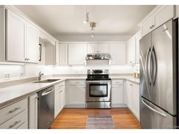 Well-lit kitchen featuring stainless steel appliances, white cabinets, and granite countertops at 695 S Alton Way # 9C, Denver, CO 80247