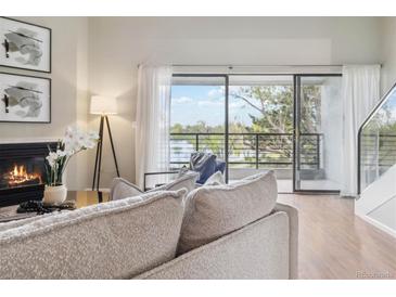 Cozy living room featuring a fireplace and access to a balcony overlooking a scenic view at 10550 W Jewell Ave # 301, Lakewood, CO 80232