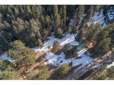 Aerial view of property showing home nestled in snowy woods at 5925 Herzman Dr, Evergreen, CO 80439