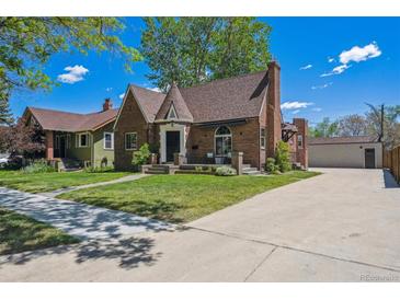 Charming brick home featuring a well-maintained lawn, a turret and a long driveway leading to a detached garage at 4434 Grove St, Denver, CO 80211