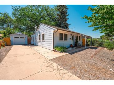 Charming light blue single-story home with a detached garage and a long driveway on a sunny day at 2205 S King St, Denver, CO 80219