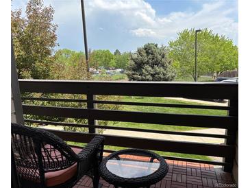 Relaxing balcony featuring a bistro set with views of green trees and distant landscaping at 539 Wright St # 203, Lakewood, CO 80228