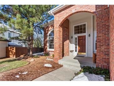 Brick house with a covered porch and a landscaped yard at 317 Ingleton Ct, Castle Pines, CO 80108