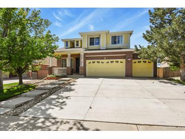 Inviting two-story home with brick accents, covered porch, and a large driveway for ample parking at 20928 E Hamilton Ave, Aurora, CO 80013