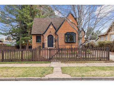 Charming brick home featuring a well-manicured lawn and a quaint picket fence at 2910 Clermont St, Denver, CO 80207