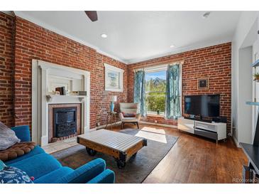 Bright living room featuring exposed brick, hardwood floors, and a decorative fireplace for a cozy atmosphere at 1438 N Franklin St # 100, Denver, CO 80218