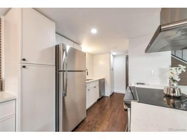 Bright kitchen featuring stainless steel appliances, white cabinets, and hardwood floors at 3355 S Flower St # 95, Lakewood, CO 80227
