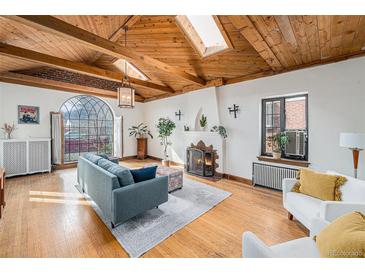 Bright living room with vaulted wood ceilings, fireplace, and large arched window at 2646 Colorado Blvd, Denver, CO 80207