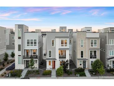 Row of modern three-story homes featuring sleek architecture, and well-maintained front yards at 12261 Farmview St, Thornton, CO 80241