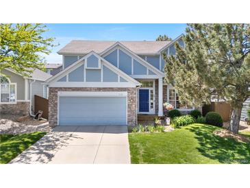 Charming exterior of a well-maintained two-story home with blue accents, stone details and a manicured front yard at 3102 White Oak Trl, Highlands Ranch, CO 80129