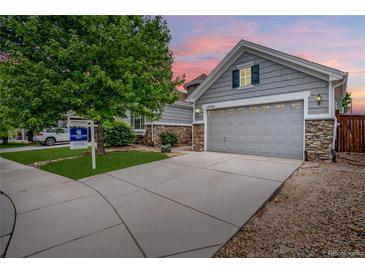 Charming gray home boasting stone accents and a two-car garage, set against a colorful twilight sky at 15502 E Flower Mound Pl, Parker, CO 80134