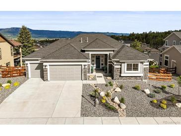 Beautiful home with a three-car garage, manicured rock garden, and attractive contrasting stone and siding accents at 16312 Morning Rise Ln, Monument, CO 80132