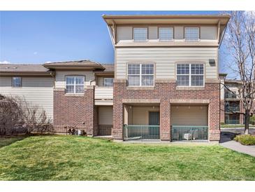 Inviting exterior of townhome featuring brick accents, private covered porch, and lush green lawn at 3866 S Dallas Cir # 201, Aurora, CO 80014
