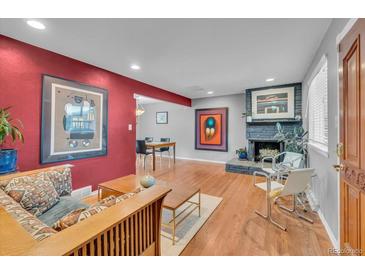 Inviting living room features a gray fireplace, hardwood floors, and charming furniture at 1648 S Locust St, Denver, CO 80224