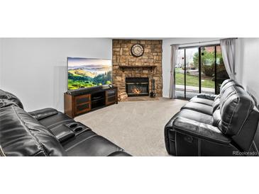 Inviting living room features a stone fireplace, plush seating, and a sliding door to the outdoors at 3546 S Depew St # 103, Denver, CO 80235