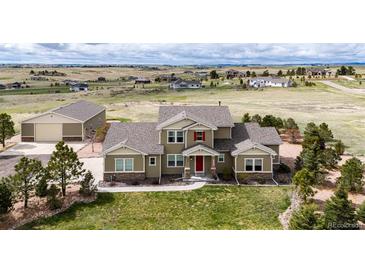 Inviting two-story home with a lush lawn, complemented by professional landscaping and a spacious detached garage at 575 Heritage Trl, Elizabeth, CO 80107