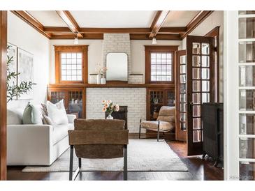 Bright living room with white sofa, fireplace with mantel, hardwood floors and coffered ceiling at 1620 Dahlia St, Denver, CO 80220